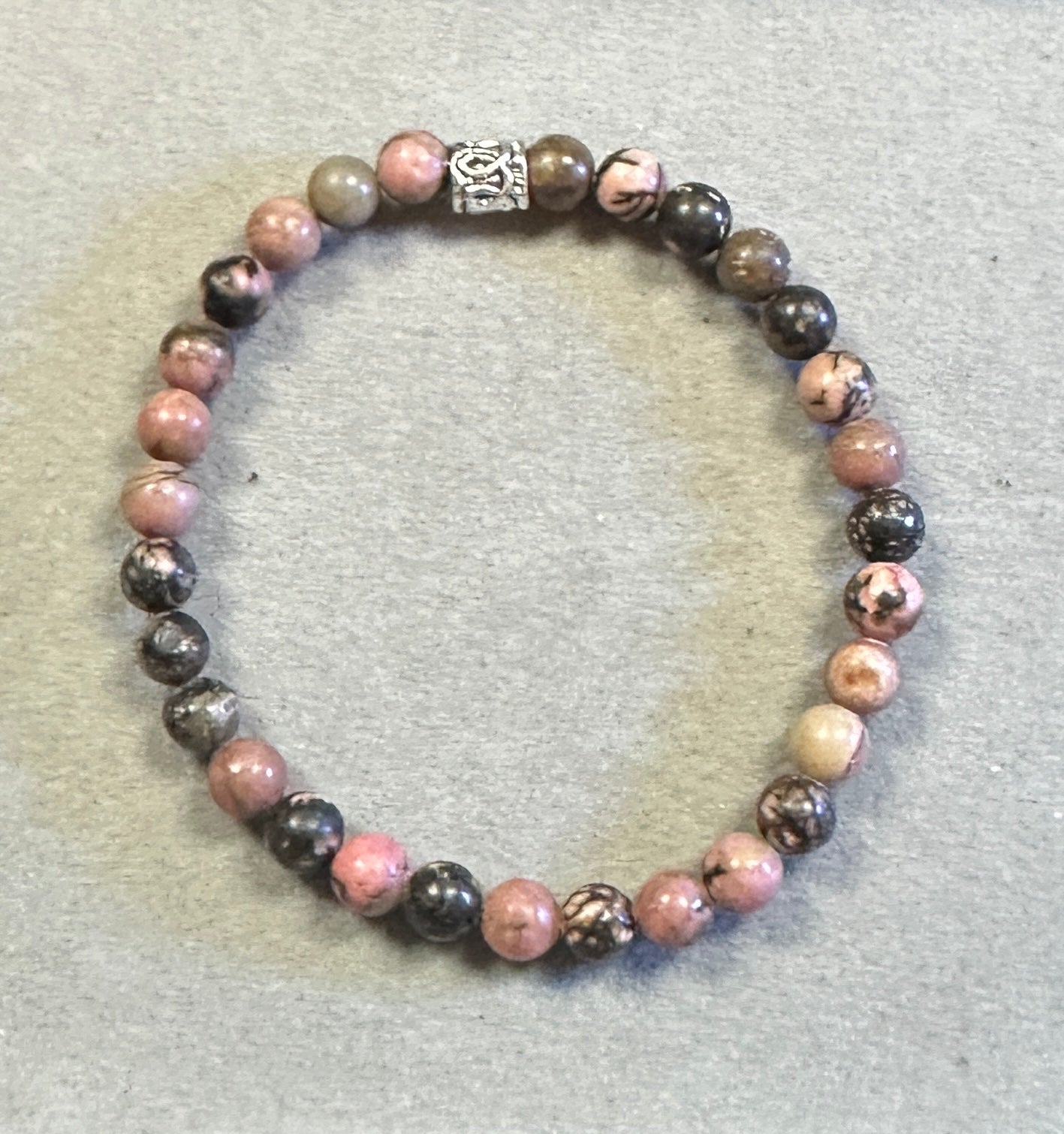 Beaded bracelet with pink and black beads on a gray background