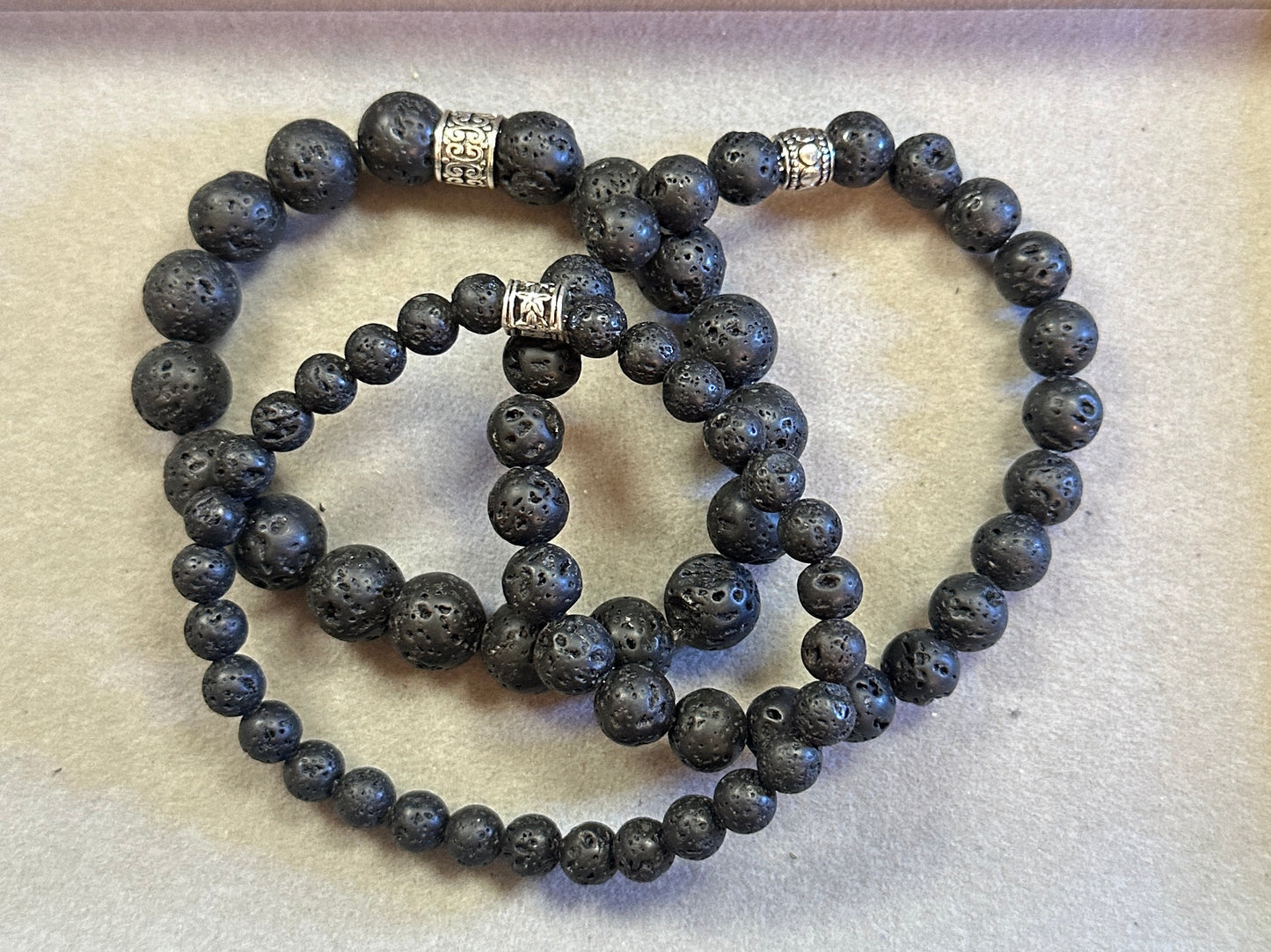 Set of black beaded bracelets with silver charms on a light background