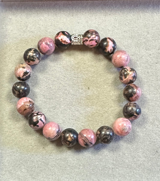 Beaded bracelet with pink and black beads on a light gray background