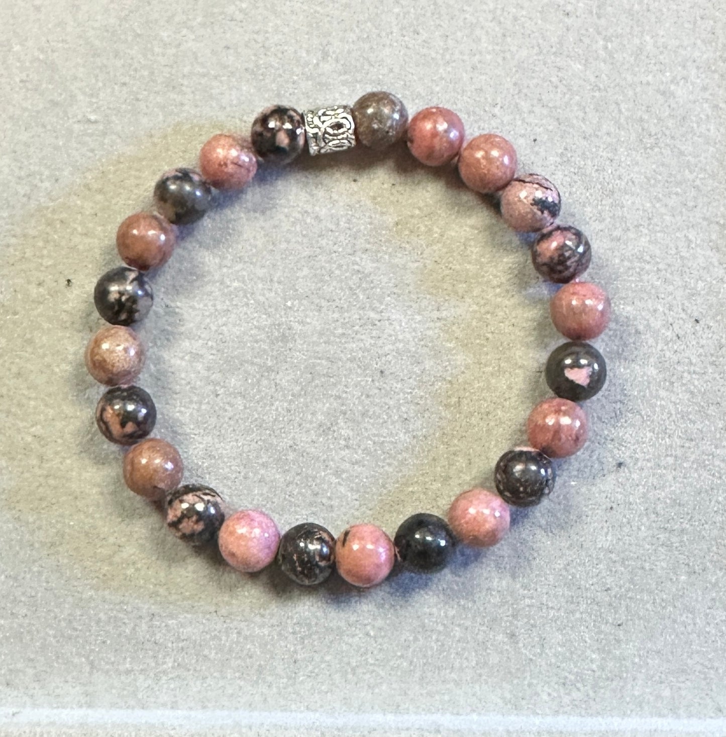 Beaded bracelet with pink and black beads on a light gray background