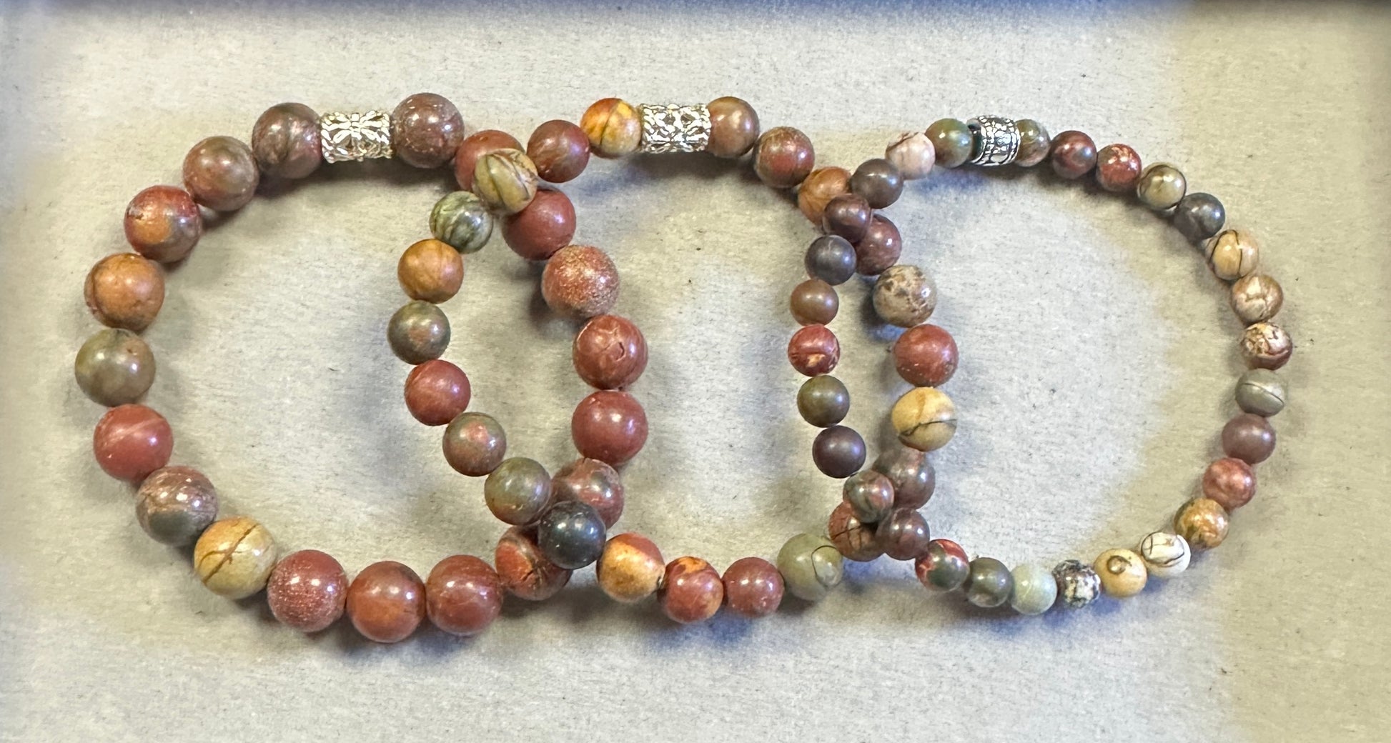 Three beaded bracelets with metal clasp on a textured surface