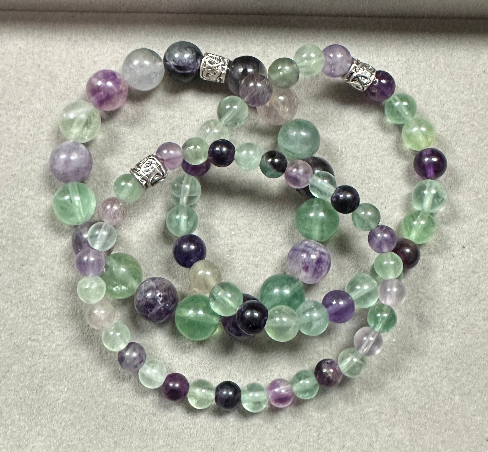 Set of beaded bracelets with purple, green, and black beads on a light gray background