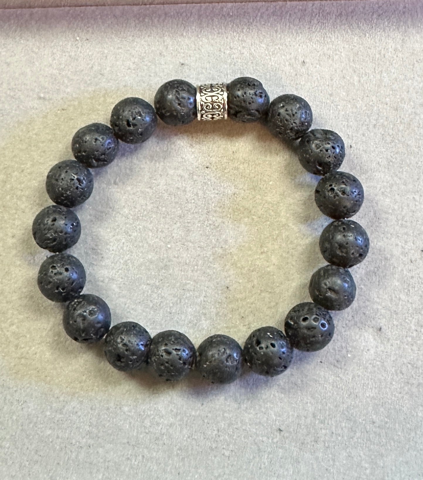 Black beaded bracelet with a silver clasp on a light gray background