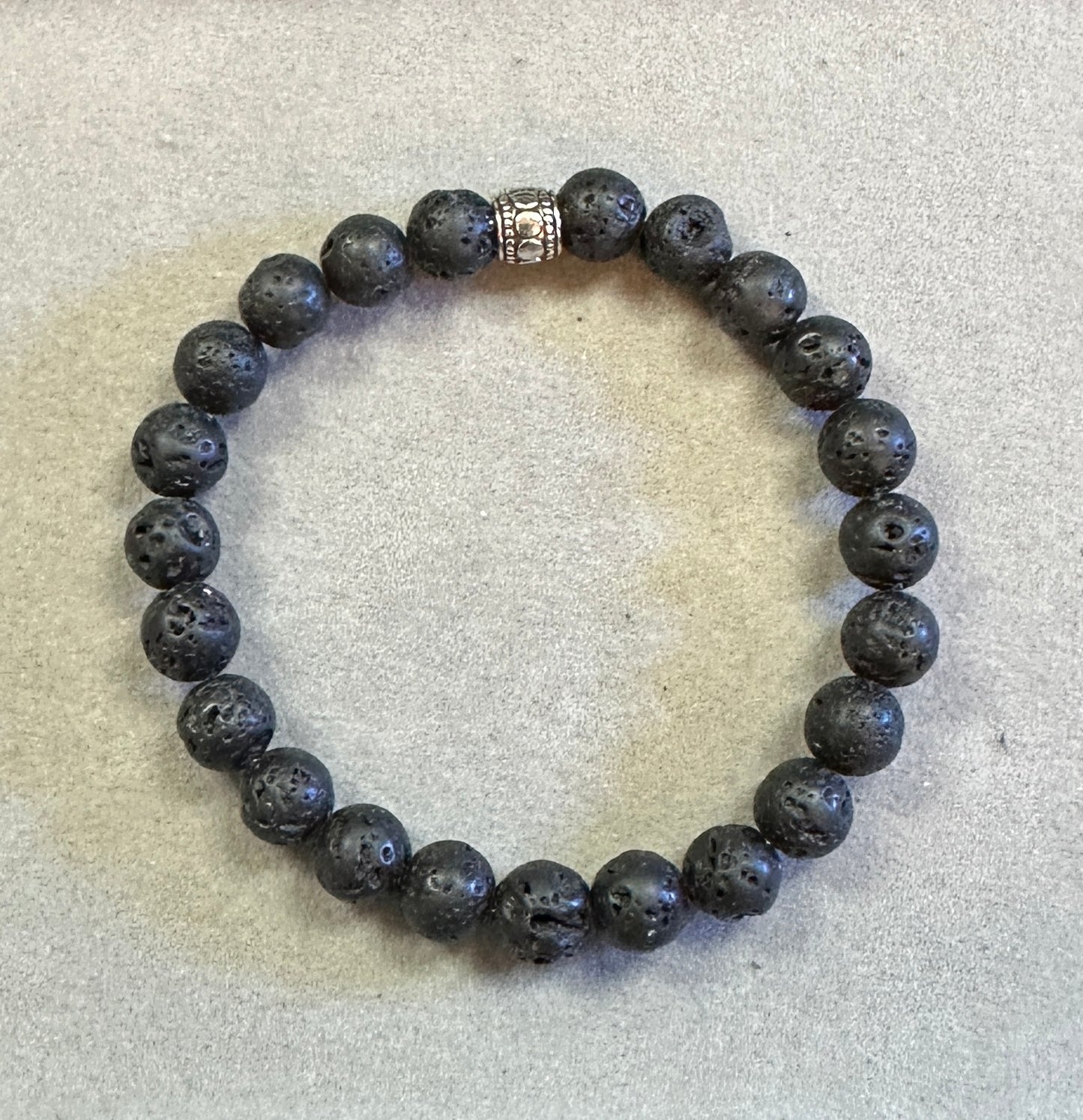 Lava stone bracelet with a metal clasp on a textured surface