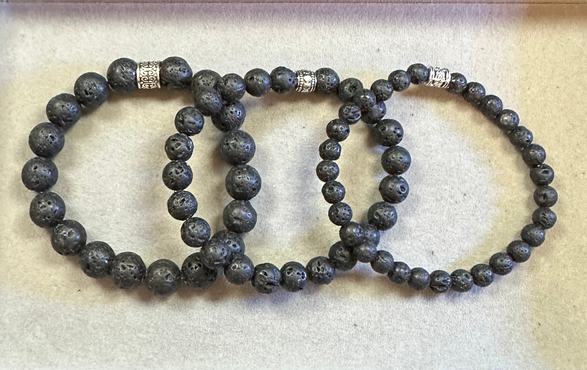 Three black beaded bracelets on a light beige background