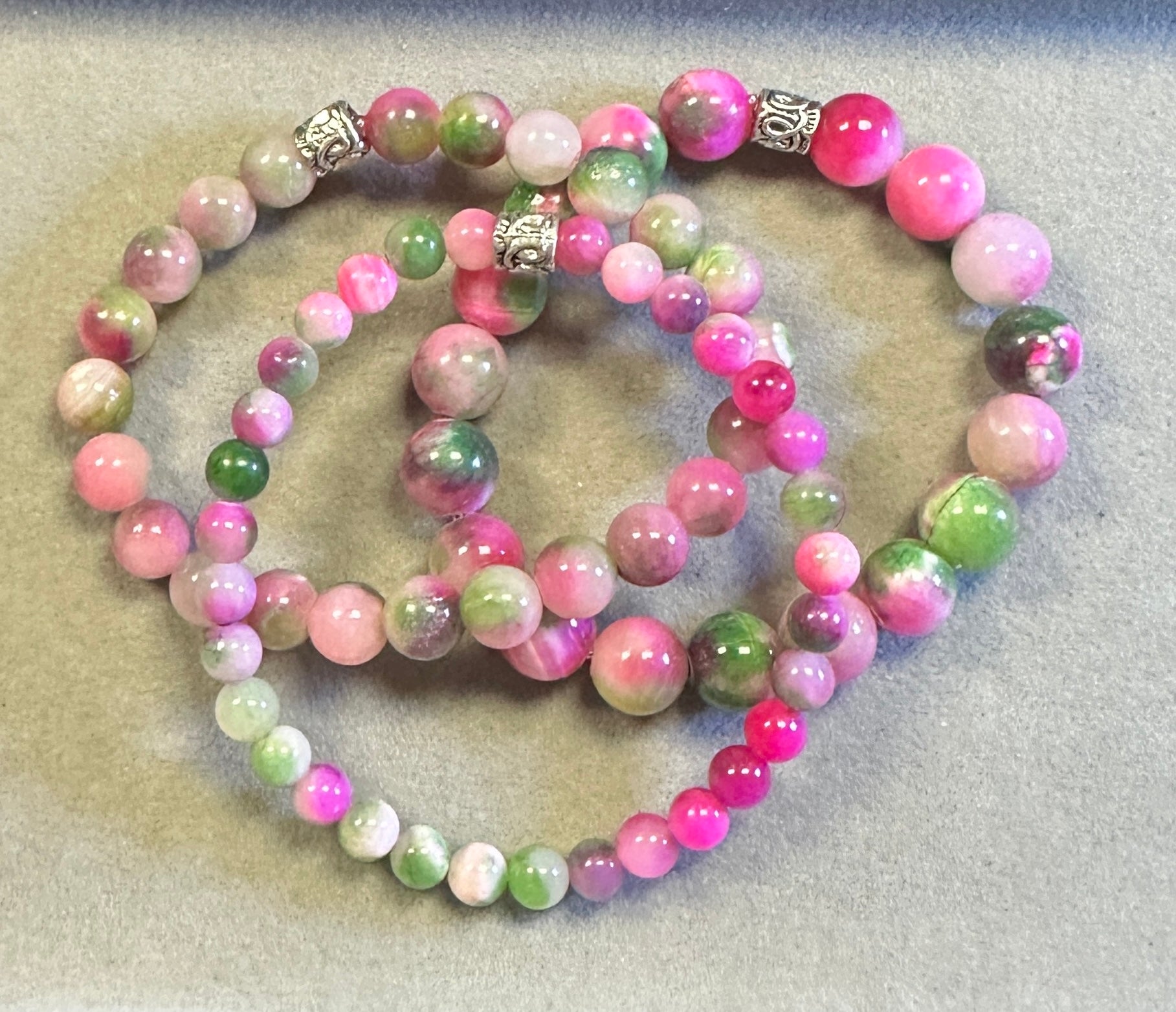 Set of pink and green beaded bracelets on a textured surface