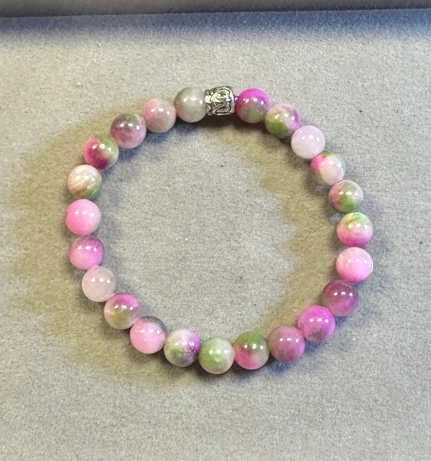 Beaded bracelet with pink and green beads on a textured surface