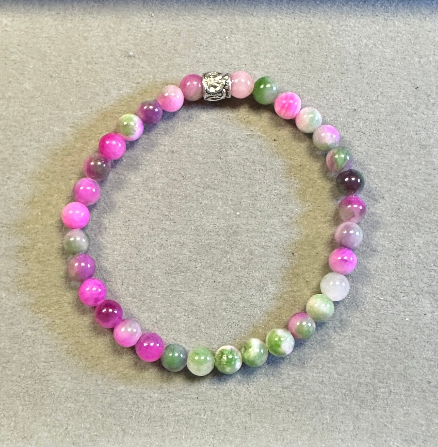 Beaded bracelet with pink, green, and purple beads on a gray surface