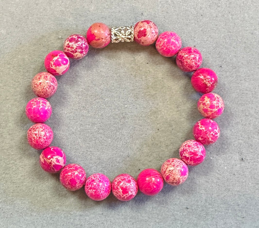 Pink beaded bracelet with a gold clasp on a gray surface