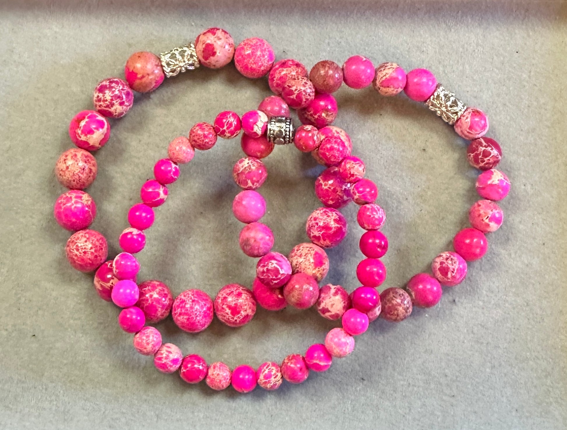 Set of pink beaded bracelets on a beige surface