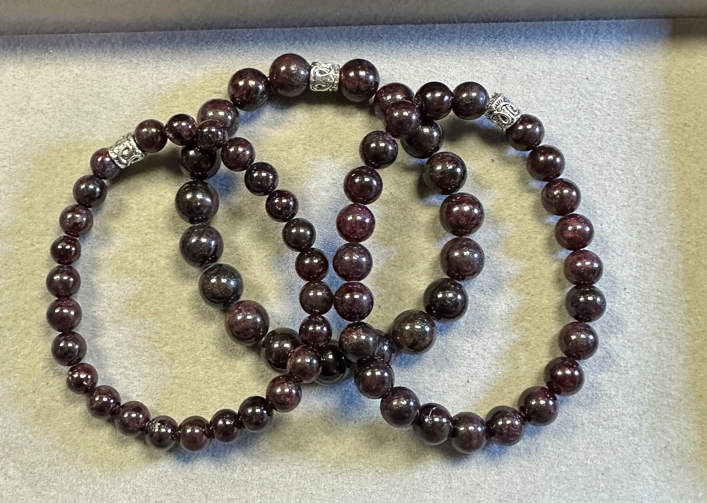 Three dark brown beaded bracelets on a light gray surface