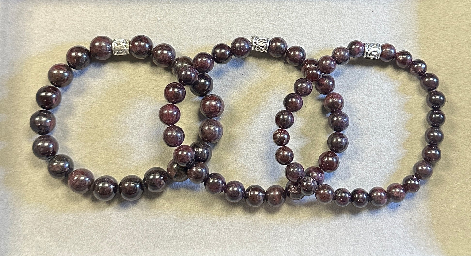 Three brown beaded bracelets on a textured beige surface