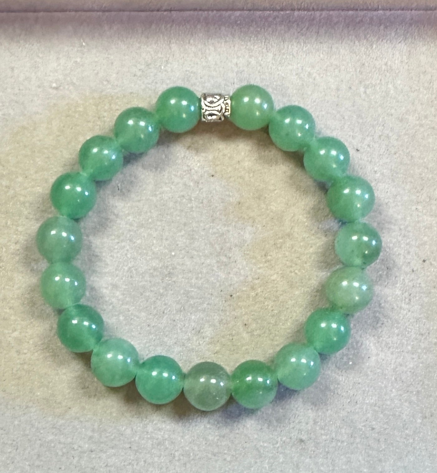 Green beaded bracelet on a light gray background