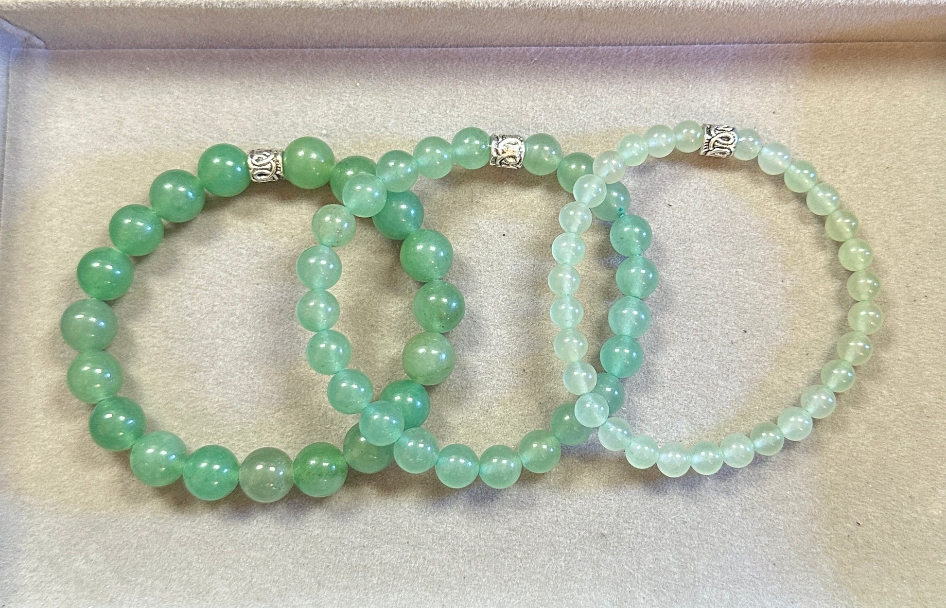 Two green beaded bracelets on a beige surface